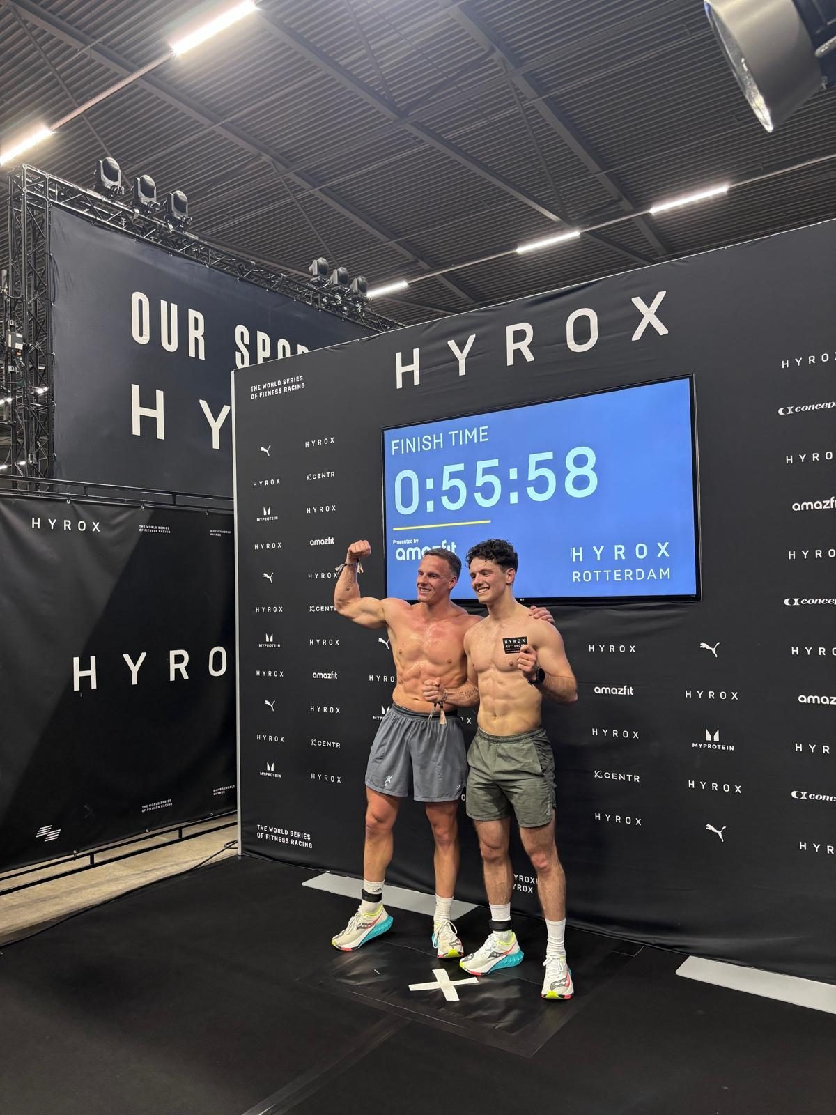 Laurens en Vince bij het finishbord van HYROX Rotterdam met hun tijd van 0:55:58