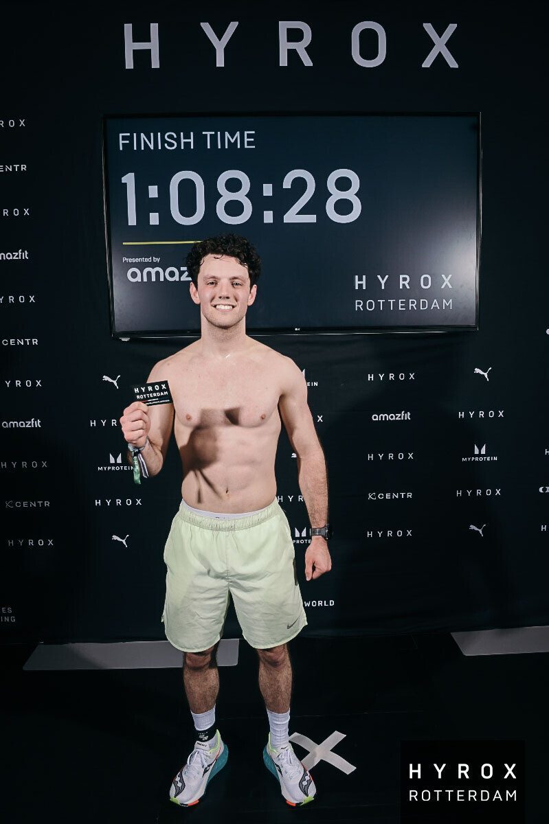 Laurens bij het finishbord van HYROX Rotterdam met een tijd van 1:08:28